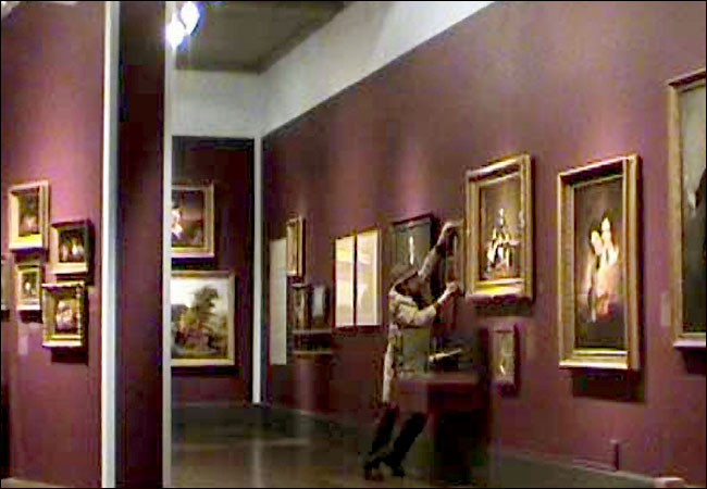 Imagem de um homem (Banksy) pendurando um quadro no museu mas deforma proibida